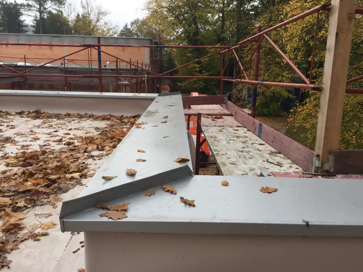Modern parapet construction on a flat roof of a residential building in the Alps to define the roof edge.