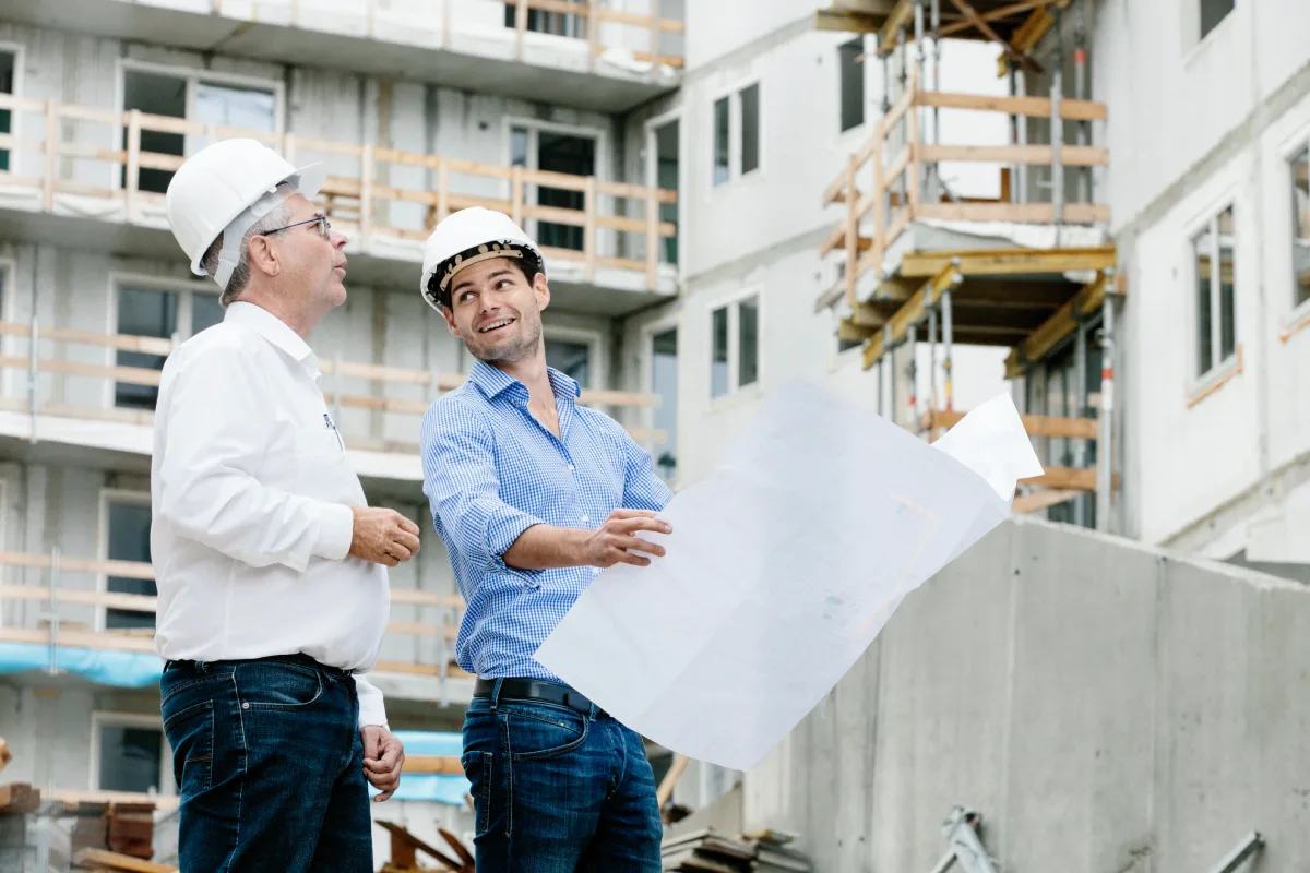Architekten bei der Besprechung der Brüstungshöhen und Bauvorschriften auf einer Baustelle.