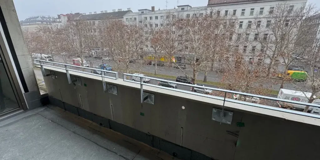 A compliant parapet wall providing fall protection on a modern terrace overlooking an urban street.